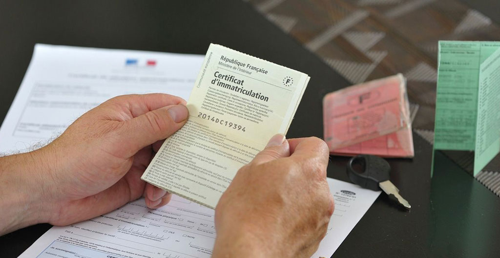 Une personne inspectant le carnet d'entretien et les documents d'une voiture d'occasion sur un capot de véhicule Une personne inspectant le carnet d'entretien et les documents d'une voiture d'occasion sur un capot de véhicule